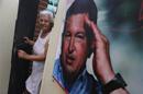 Woman smiles as she stands next to a poster of Venezuela's late President Chavez at the 23 de Enero neighbourhood in Caracas