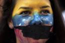 A demonstrator attends a protest with her mouth covered by tape and face painted in the colors of the Venezuelan flag in Caracas, Venezuela, Sunday, March 2, 2014. Since mid-February, anti-government activists have been protesting high inflation, shortages of food stuffs and medicine, and violent crime in a nation with the world's largest proven oil reserves. (AP Photo/Rodrigo Abd)