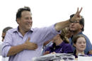 FILE- In this April 25, 2014 file photo, Juan Carlos Varela, presidential candidate for the Panamenista Party, waves to supporters during a campaign caravan through Arraijan on the outskirts of Panama City. Varela owes a debt of gratitude to a former adviser to John McCain’s ill-fated 2008 White House run for his come from behind victory in Panama’s presidential election. (AP Photo/Arnulfo Franco, File)