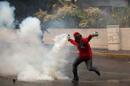 A demonstrator throws back a teargas canister fired by Bolivarian National Police after clashes broke out at an anti-government protest in Caracas, Venezuela, Thursday, May 8, 2014. Demonstrators took to the streets after a pre-dawn raid by security forces that broke up four camps maintained by student protesters and arrested more than 200 people. The tent cities were installed more than a month ago in front of the offices of the United Nations and in better-off neighborhoods in the capital to protest against President Nicolas Maduro's socialist government. (AP Photo/Alejandro Cegarra)