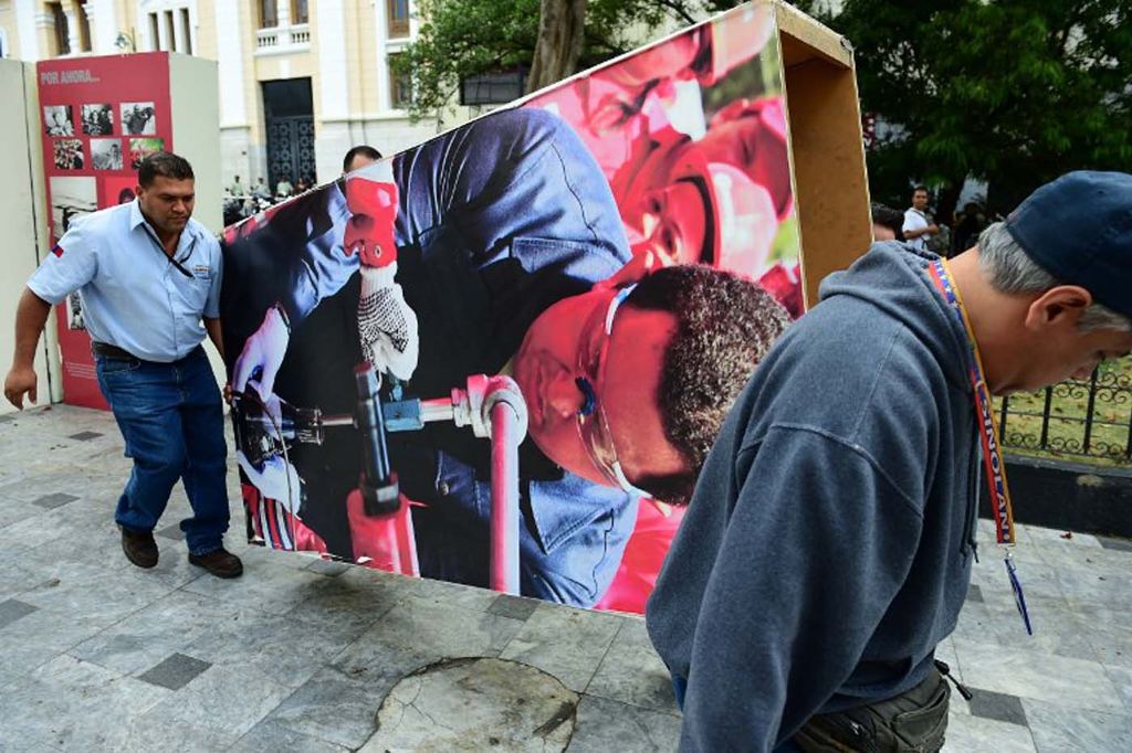 Venezuelan National Assembly employees remove from the building  pictures of late President Hugo Chavez, in Caracas on January 6, 2016. Venezuela's opposition on Tuesday broke the government's 17-year grip on the legislature and vowed to force out President Nicolas Maduro despite failing for the time being to clinch its hoped-for "supermajority." AFP PHOTO/RONALDO SCHEMIDT / AFP / RONALDO SCHEMIDT