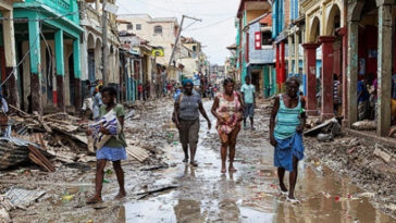 People walk along a street in downtown as clean up from Hurricane Matthew continues in Jeremie, Haiti, October 6, 2016. Picture taken October 6, 2016.